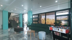 A spacious lobby with a foosball table, a green sofa, and a marble floor. - Sans Hotel near Enchanted Kingdom (Santa Rosa)