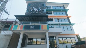 A multi-story hotel with a modern design, featuring a prominent sign for "SANS HOTELS" and a visible entrance with a staircase. - Sans Hotel near Enchanted Kingdom (Santa Rosa)