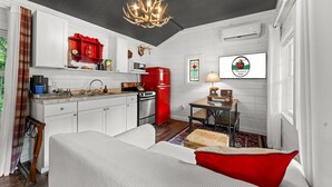 A compact kitchen with white cabinetry, a red refrigerator, and a chandelier. - Stylish Creekside Escape | Pool + Hot Tub (Blue Eye)