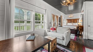 A cozy room with a white sofa, a wooden coffee table, and a large window with curtains. - Stylish Creekside Escape | Pool + Hot Tub (Blue Eye)
