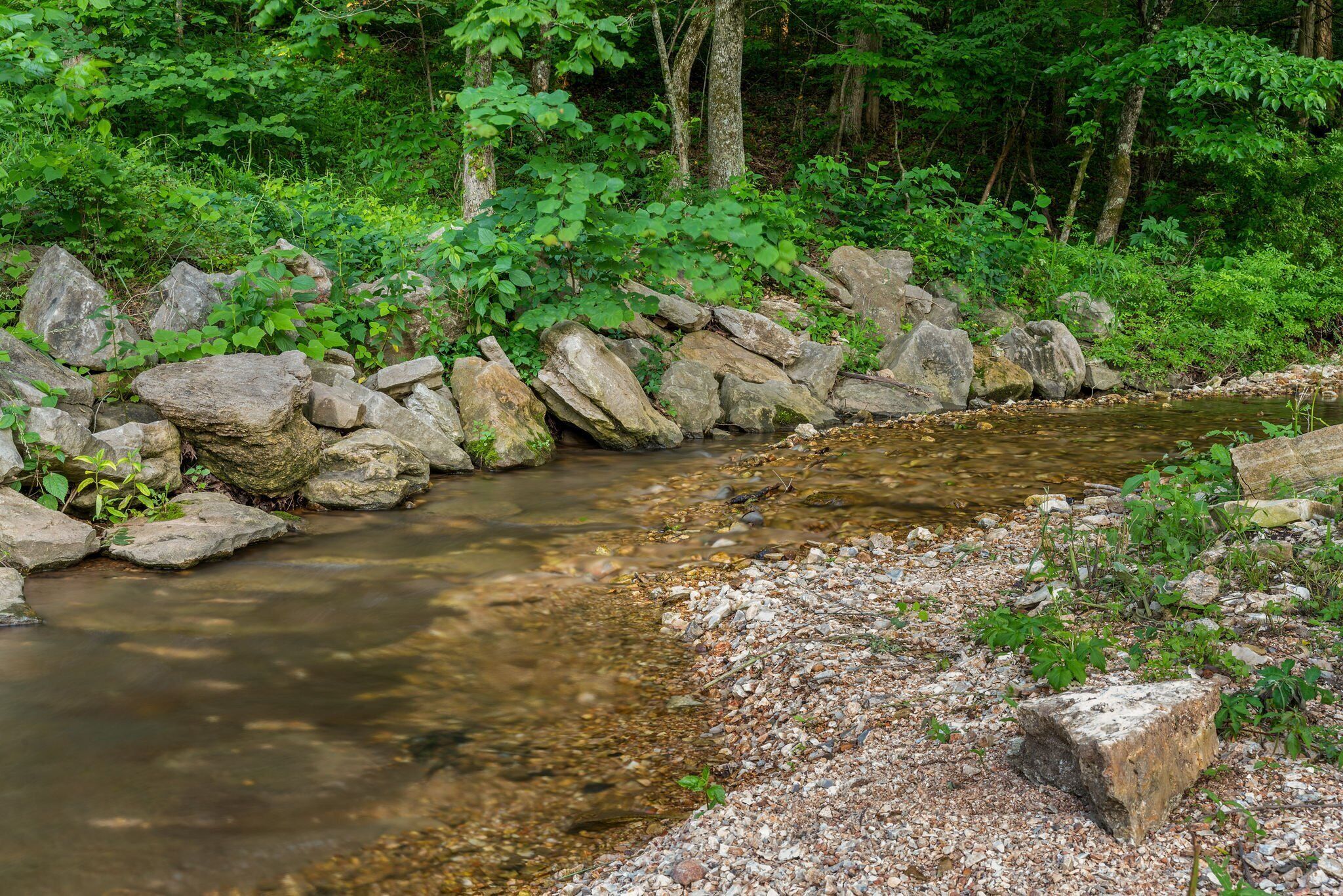 Un cours d’eau naturel, bordé de rochers et de végétation.