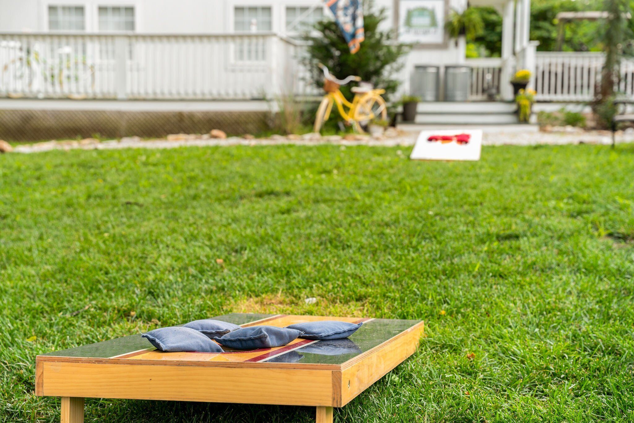 A wooden bench with pillows on a grassy lawn.