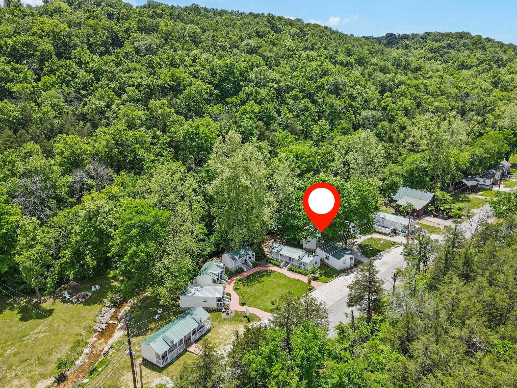 A cluster of cabins surrounded by dense forest, with a red location marker indicating the area.