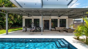 A modern outdoor pool area with a covered patio, seating, and a view of the surrounding greenery. - Charming Villa, 5 min walk to Marino Ballena Beach (Uvita)