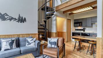 A modern interior with a sofa, a chair, a bar area, and a kitchen.