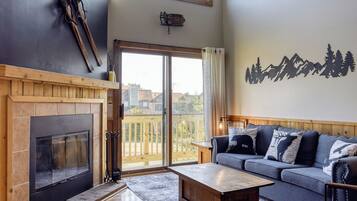 A spacious living room with a fireplace, a large window, a sofa, and a view of the outdoors.