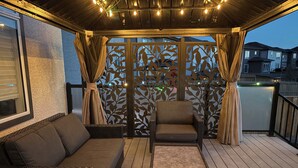 A covered outdoor seating area with a sofa, chairs, and a small table.