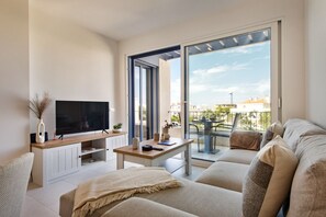 A modern living room with a flat-screen TV, a wooden coffee table, and a sofa.