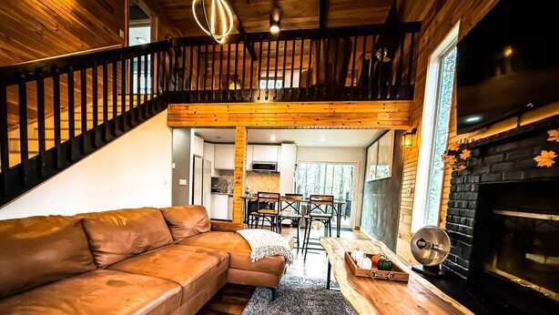Un salón acogedor con un sofá de cuero, una mesa de comedor de madera y una chimenea.