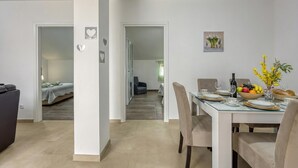 Ein Essbereich mit einem Tisch für vier Personen, einer Couch und einem Bett im Hintergrund.