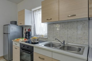 A modern kitchen with stainless steel appliances, a double sink, and light wood cabinetry.