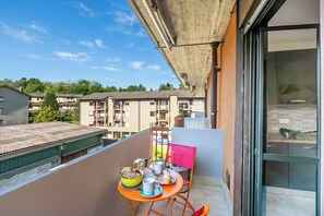 A balcony with a table set for breakfast, a chair, and a view of surrounding buildings.
