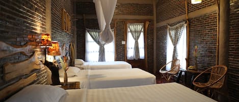 A room with two beds, a wooden headboard, a hanging chair, and a table with a vase.