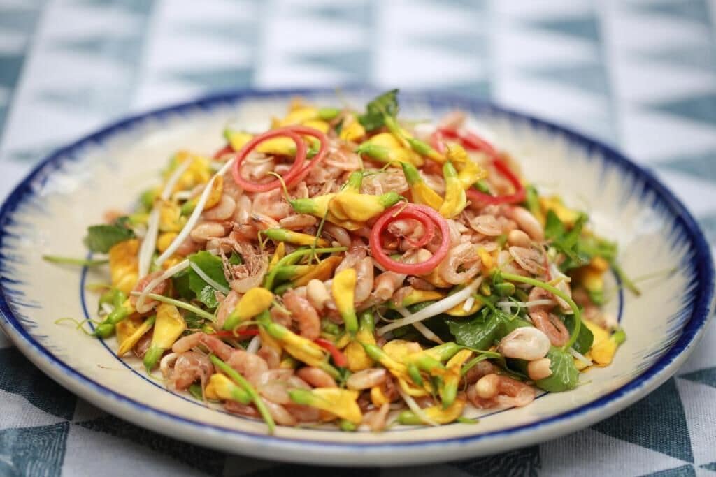En tallrik med blandad sallad, innehållande olika grönsaker och örter.