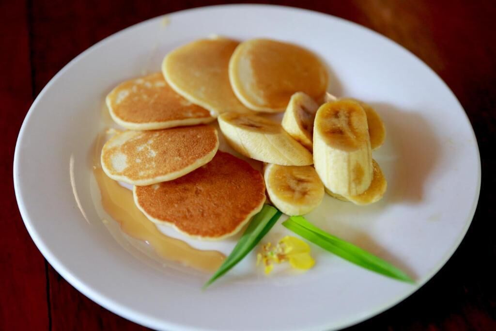 A white plate with pancakes and sliced bananas.