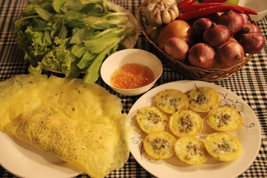 A table with a checkered tablecloth, a plate of food, and a basket of vegetables.