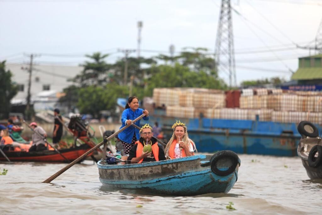 A small boat with three people wearing crowns, floating on water.