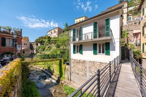 A residential area with a stone pathway leading to a wooden bridge, surrounded by buildings with balconies and green shutters. - Middle Apartment Vernazza, Vernazza, Italy (Vernazza)