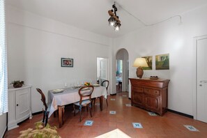 A dining area with a table set for four, a wooden cabinet, and a hallway leading to another room.