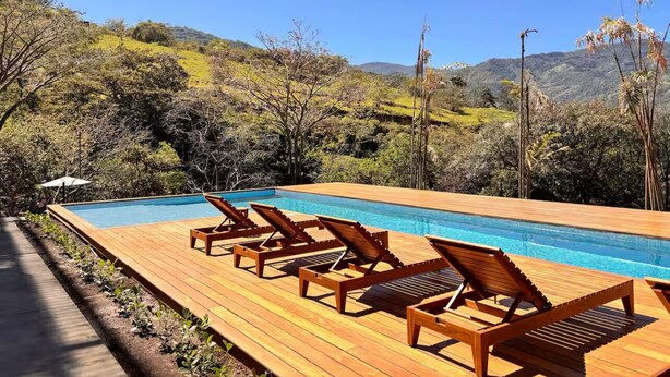 A wooden deck with a pool and lounge chairs overlooking a hilly landscape. - Beautiful Studio (Santa Ana)