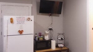 A compact kitchen with a refrigerator, microwave, and a small shelf with various items. - Charming studio with AC and WiFi in pleasant Gervais. (Gervais)