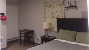 A bedroom with a bed, a desk, a chair, a lamp, and an air conditioner. - Charming studio with AC and WiFi in pleasant Gervais. (Gervais)