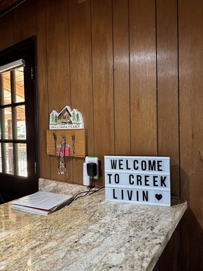 A wooden cabin interior with a welcome sign, a cabin model, and a power outlet.
