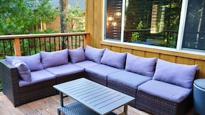 A wooden deck with a sectional sofa and a small table. - Creekside Cabin+Fire Pit+Lakes Nearby+Wine Tasting+Bear Valley Ski Resort (Arnold)