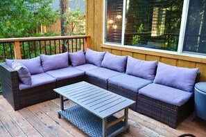 A wooden deck with a sectional sofa and a small table. - Creekside Cabin+Fire Pit+Lakes Nearby+Wine Tasting+Bear Valley Ski Resort (Arnold)