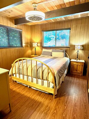 A wooden-paneled bedroom with a bed, two bedside tables, and a ceiling fan. - Creekside Cabin+Fire Pit+Lakes Nearby+Wine Tasting+Bear Valley Ski Resort (Arnold)