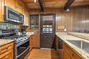 A kitchen with wooden cabinets, a stainless steel range, a microwave, and a stove.