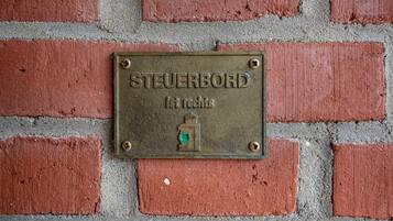 Una placa metálica con la inscripción 'STEUERBORD 1st rights' montada en una pared de ladrillo.