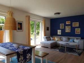 A modern living room with a sofa, a dining table, and artwork on the walls.