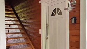 A wooden staircase leading to an upper level, a white door with a small window, and a wall-mounted light fixture. - Holiday Home 'Sonnenweide, 85qm' with Private Terrace, Shared Garden and Wi-Fi (Salem)