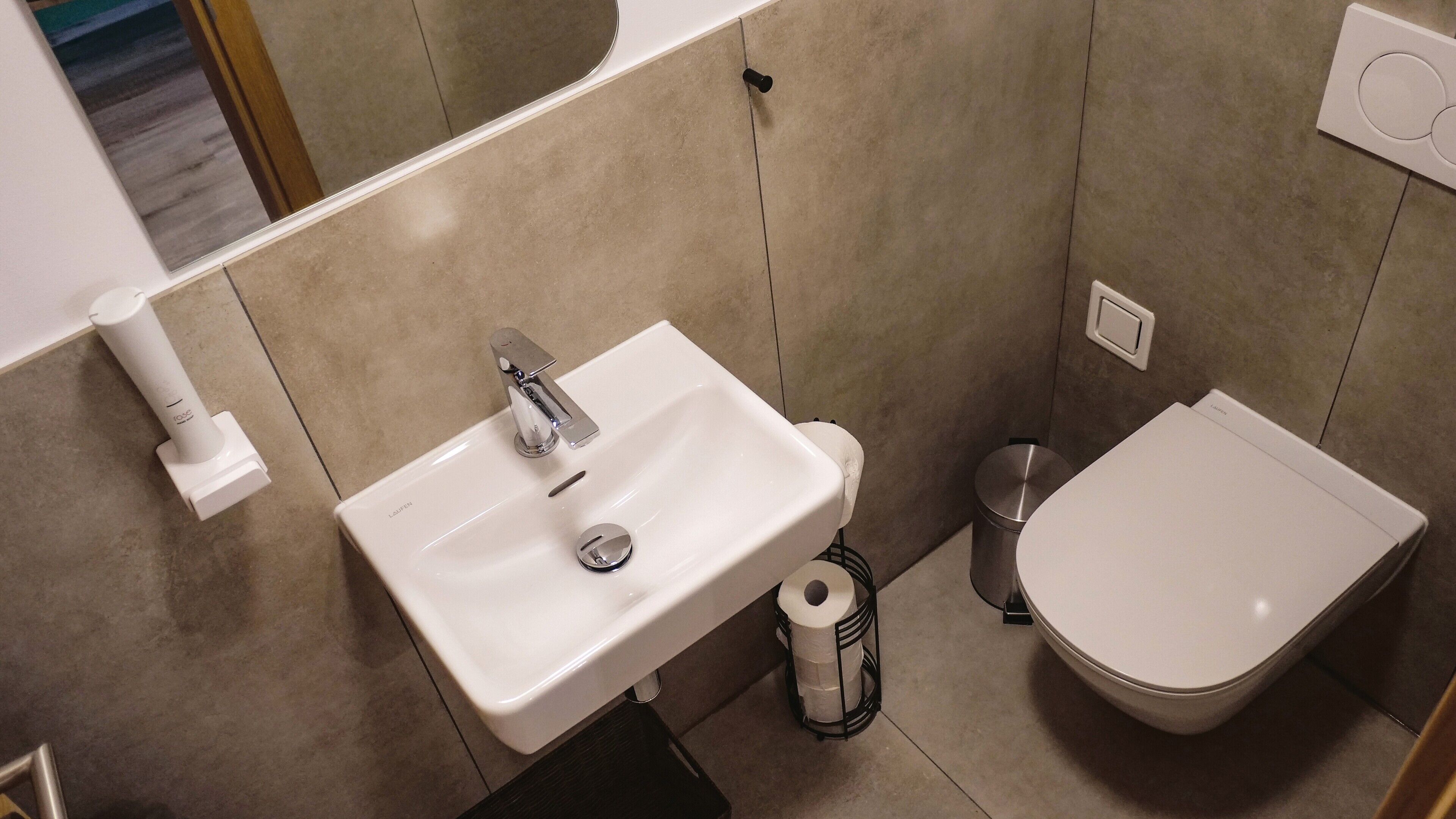 Un baño con un lavamanos blanco, un inodoro y un cubo de basura.