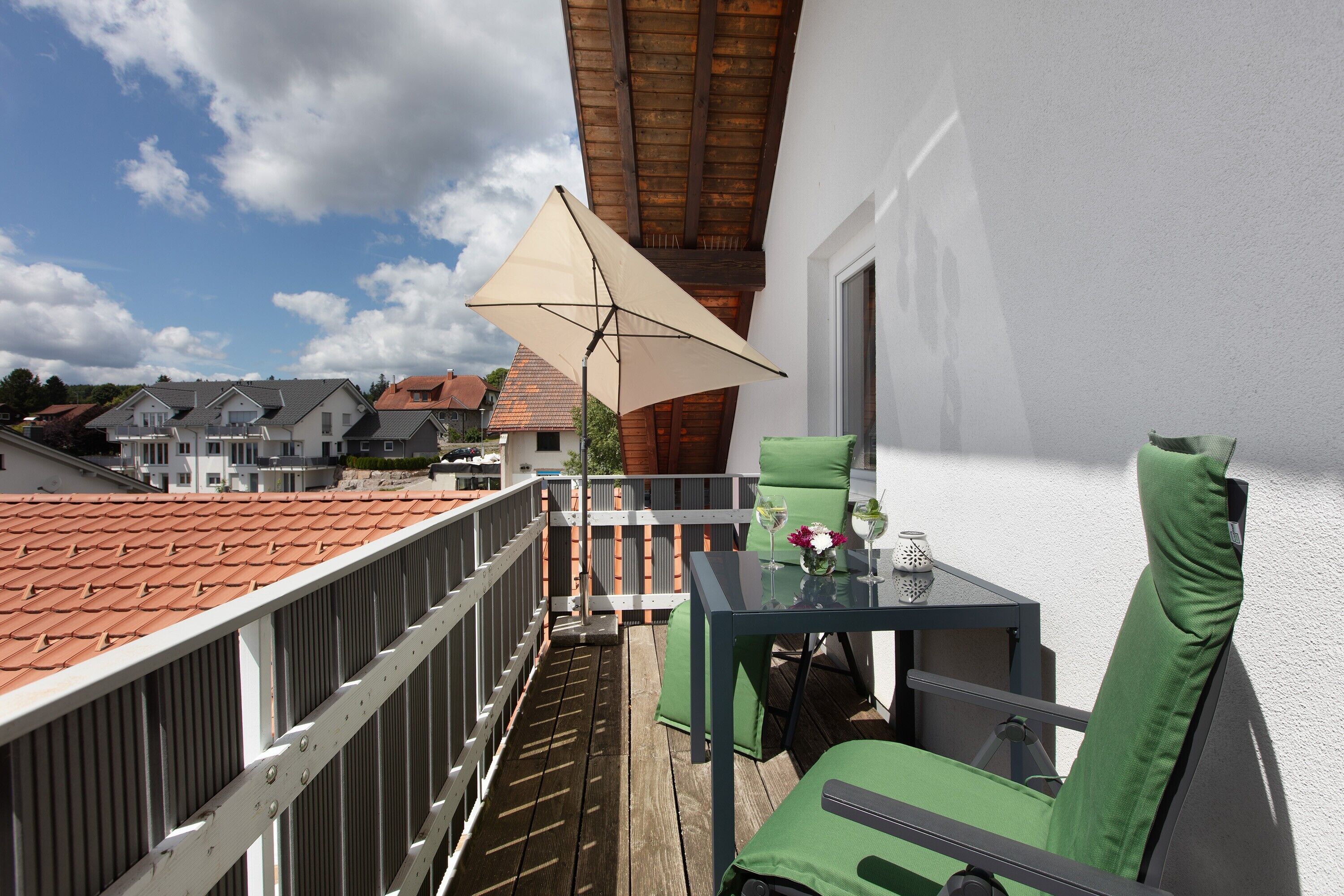 A balcony with a table, chairs, and an umbrella.