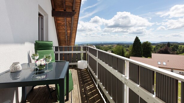 Ein Balkon mit Tisch, Stühlen und Blick auf die Landschaft.