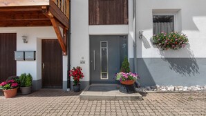 Ein Gebäude mit einem Holzbalkon, einer grauen Tür und Blumenkästen im Erdgeschoss.