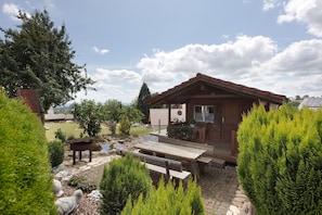 A wooden cabin with a patio, outdoor seating, and a pond.