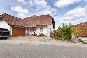 Une maison à deux étages avec un toit en tuiles, un garage et une allée pavée.