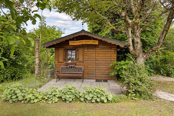 A wooden cabin with a bench outside, surrounded by greenery. - Apartment 'Ilona' with Shared Terrace, Garden and Wi-Fi (Bonndorf im Schwarzwald)