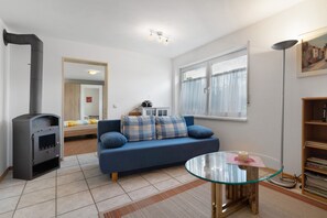 Ein Wohnzimmer mit einer Couch, einem Glastisch, einem Bücherregal, einem Kamin und einem Fenster.