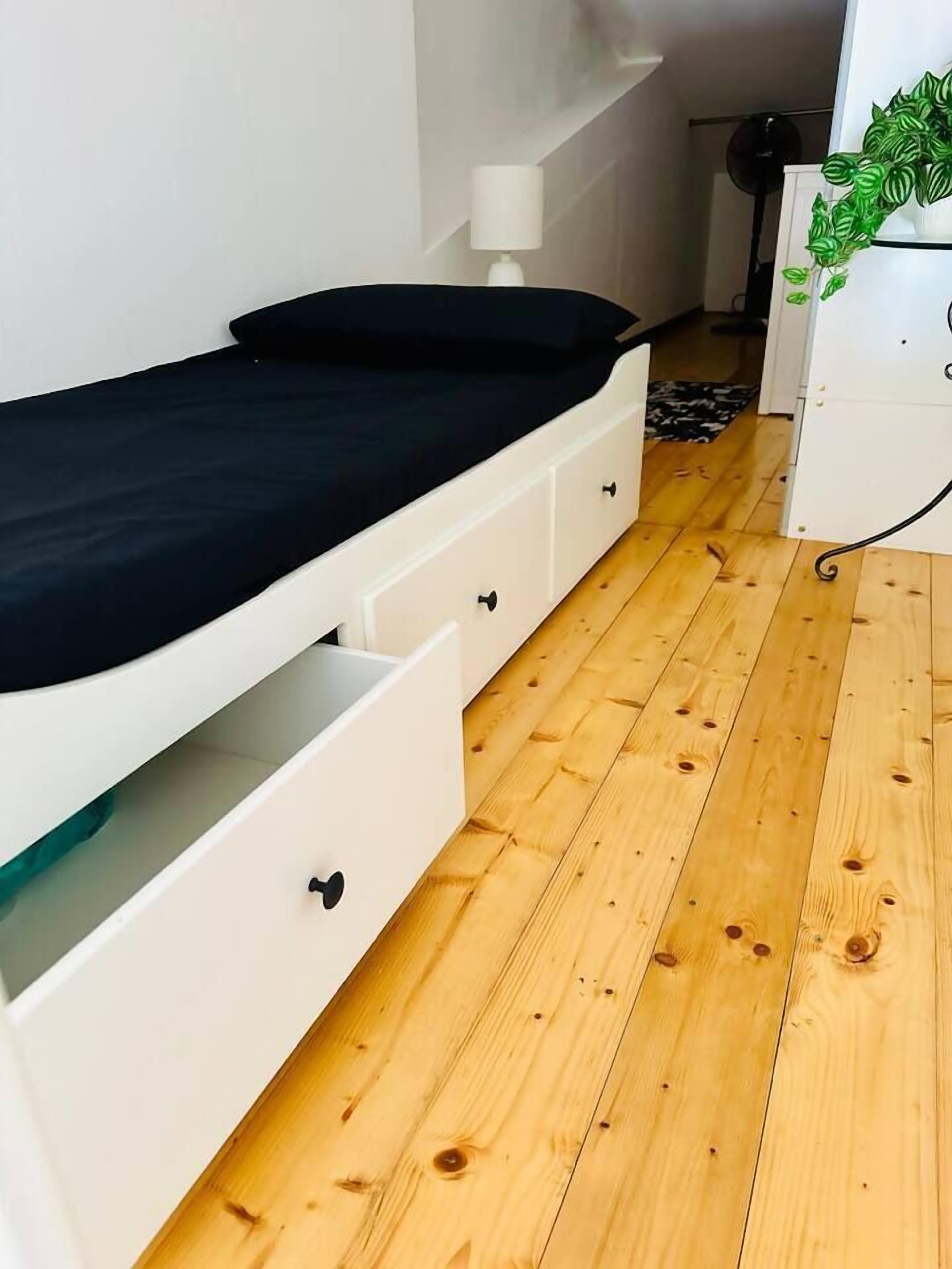 A compact room with a bed, a white dresser, and a small desk.