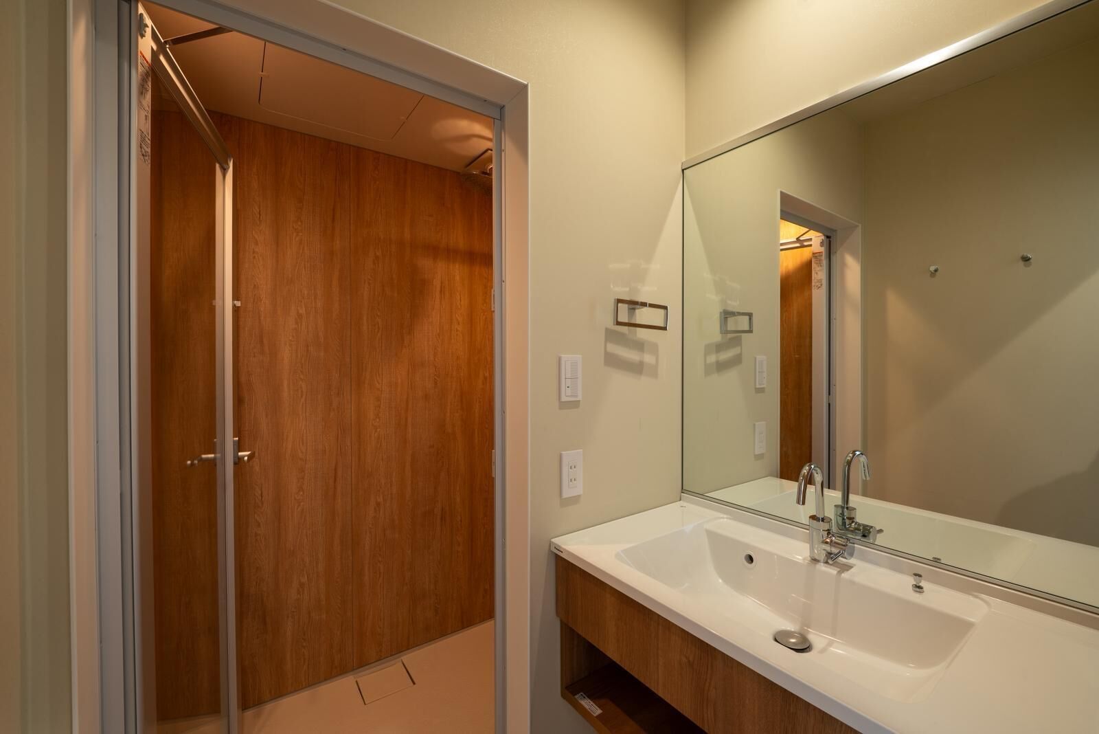 A bathroom with a wooden closet, a large mirror, and a white sink.