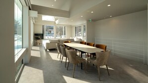 Een modern interieur met een eethoek, banken en grote ramen.