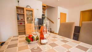 Une table à manger recouverte d’une nappe à carreaux, une bouteille de vin, deux verres à vin et un saladier rempli de fraises.