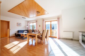 Un vaste espace de vie comprenant une table à manger en bois, des chaises, un canapé et un coin cuisine avec une cuisinière.