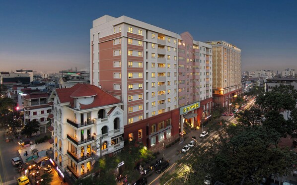 Um hotel com vários andares, combinando arquitetura moderna e tradicional, com varandas e uma entrada imponente.