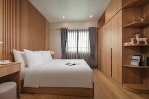Quarto bem arrumado com cama, mesa de cabeceira e guarda-roupa de madeira com prateleiras.