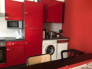 A compact kitchen with red cabinets, a microwave, a coffee maker, and a washing machine. - Apartment 'Peperoni' with Private Garden and Wi-Fi (Moos)